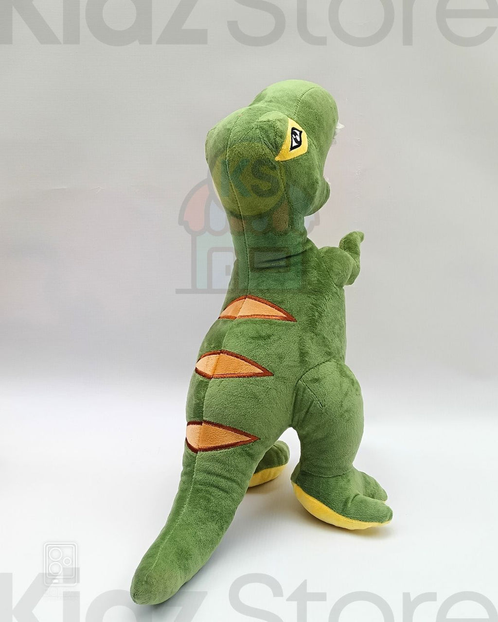 Green dinosaur plush toy with orange accents on a white background