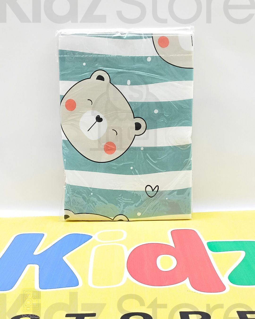 Card with a bear design on a striped background, displayed in front of a 'Kidz Store' sign.